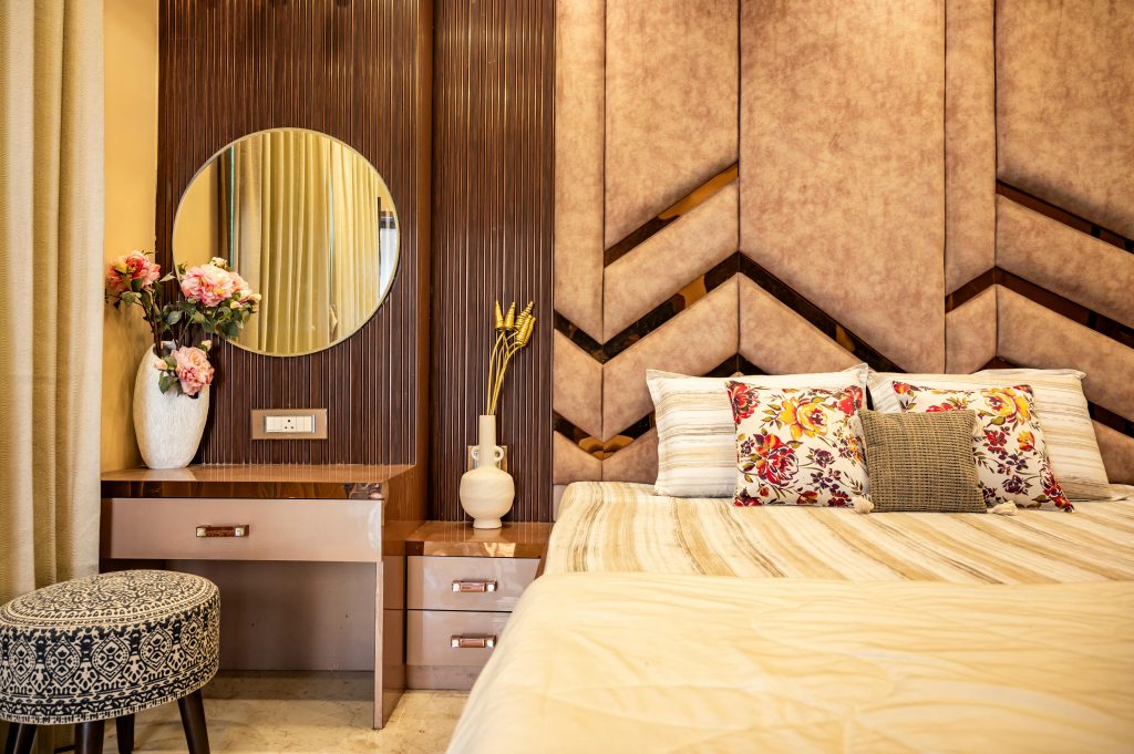Stylish bedroom interior featuring a cozy bed, floral pillows, and a chic vanity setup.